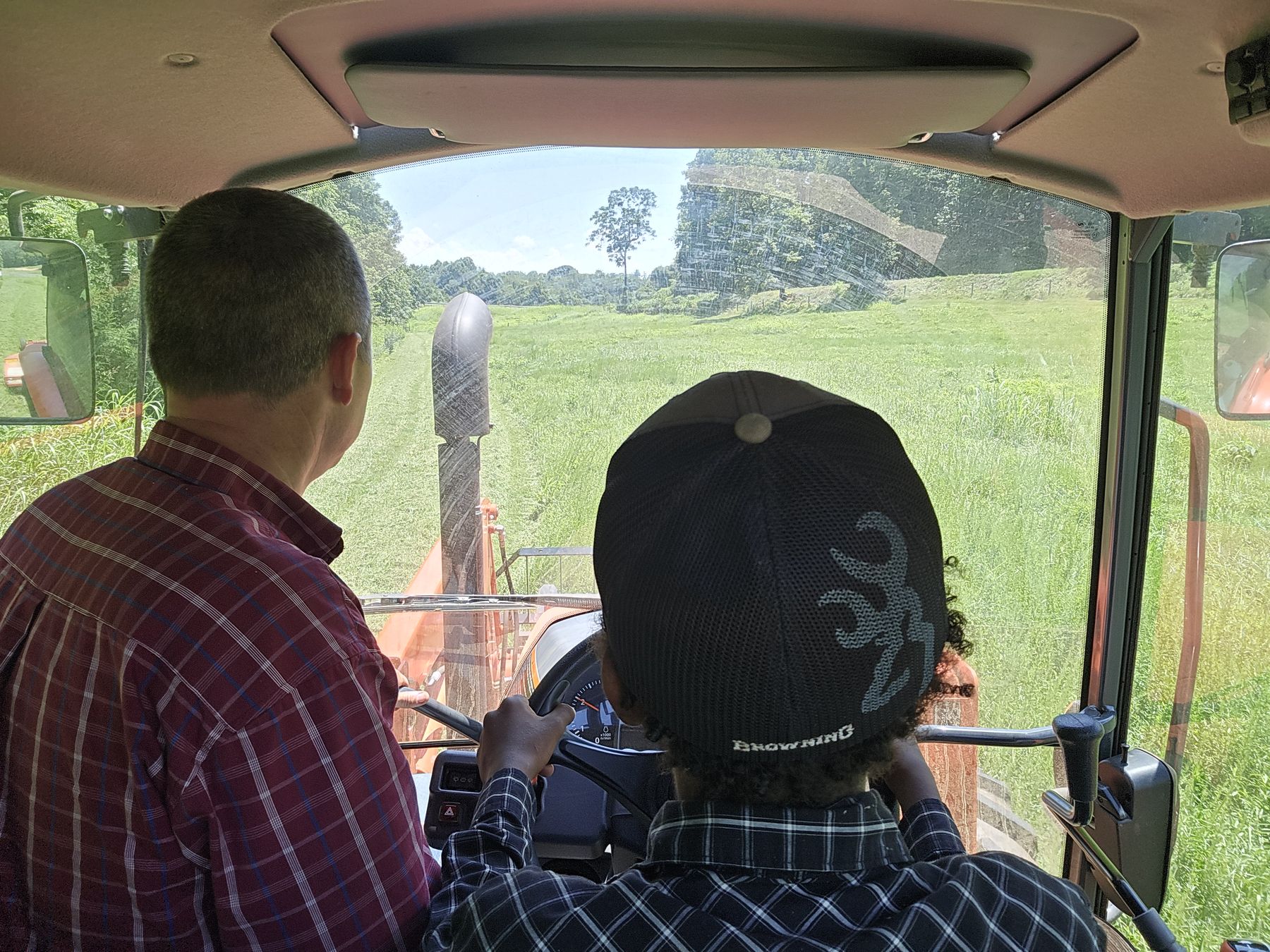 Whitney Sewell teaching one of his children to drive the tractor