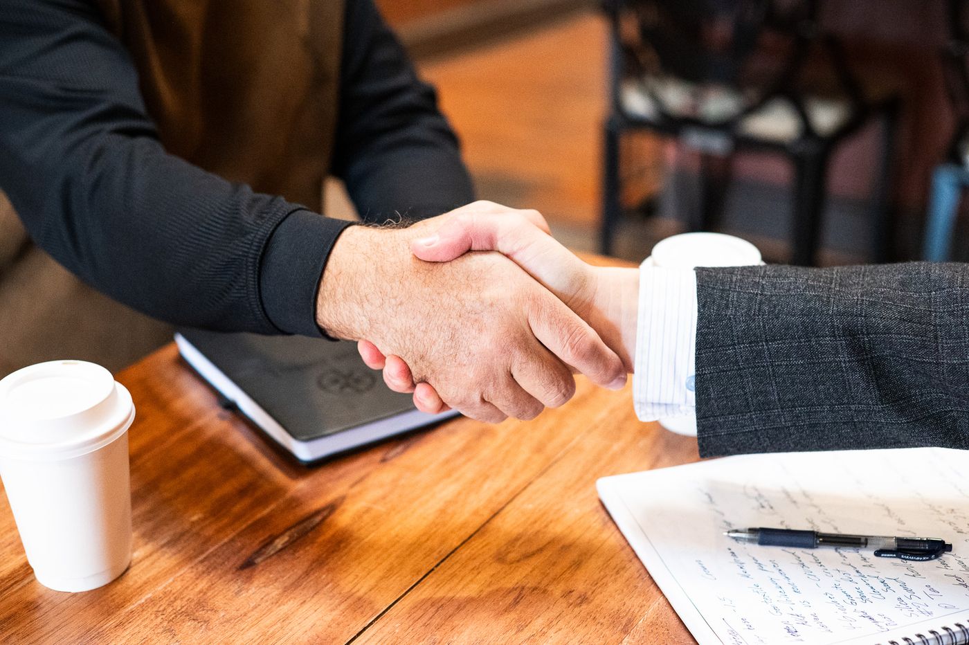 Two people shaking hands across a table